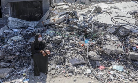 A Palestinian woman among the rubble and ash of the buildings in Rafah.