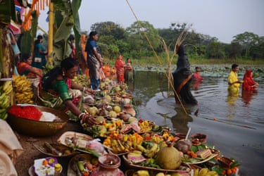 People and plates of fruit at the side of a body of water
