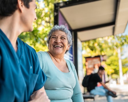 Older woman smiling at a person at a bus stop