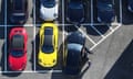 Aerial view of about seven cars on a forecourt, including one red and one yellow