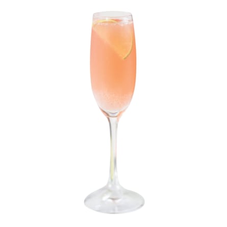 A champagne glass containing a pink cocktail with a lime slice