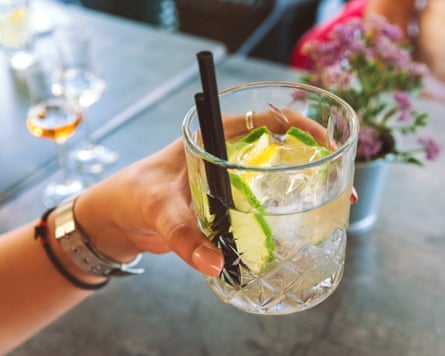 A closeup of a female hand holding a gin and tonic