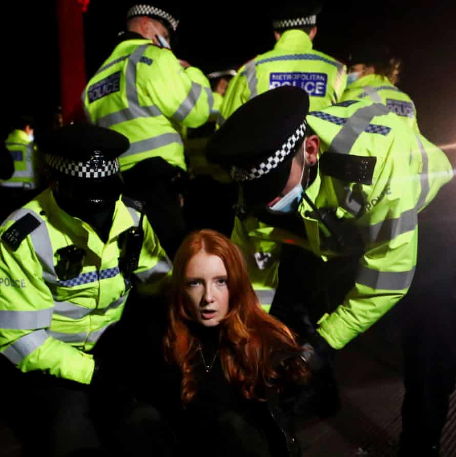 Police detain a woman as people gather at the memorial.