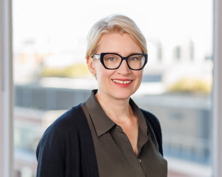 A blonde woman with short hair and glasses smiles at the camera