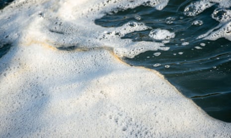 White and brown foam on water of the Thames.