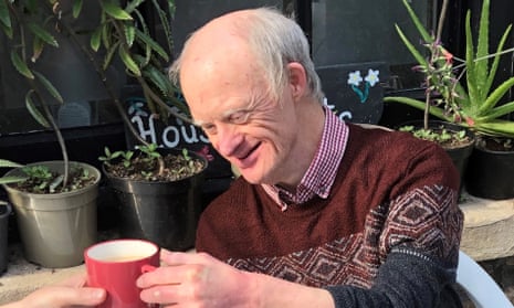 Marcus Hanlin smiling in a garden, taking a mug of tea from someone's hand
