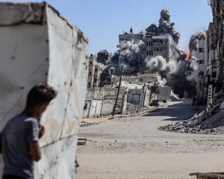 A boy watches a smoke rises from building after a strike.