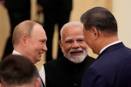 Putin, Modi and Xi stand close together in conversation