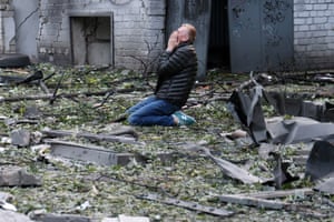 A man on his knees amid rubble