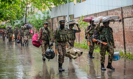 Indian paramilitary soldiers arrive in the rain to guard a venue for the distribution of Electronic Voting Machines and other election material in Srinagar, Indian controlled Kashmir, Sunday, 12 May 2024.