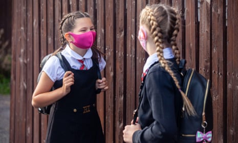 Two 10-year-old  girls chatting to each other and wearing face masks