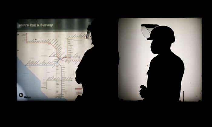 Police officers are silhouetted as they stand guard at a subway station during a protest in Los Angeles.