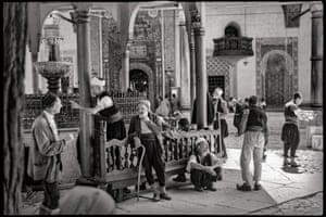 Gazi Husrev-beg Mosque, Sarajevo, Yugoslavia Men socialize at the ritual foot-washing fountain outside a mosque in Sarajevo. The out-of-focus curtain on the left edge may indicate that the photo was taken through a bus window.