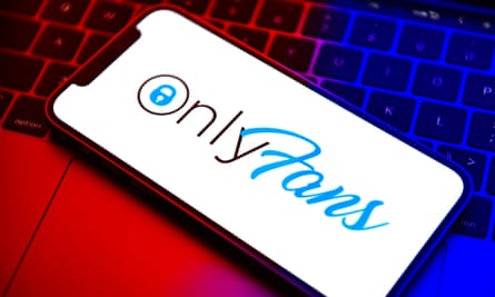 A mobile phone displaying the OnlyFans site logo resting on a laptop keyboard
