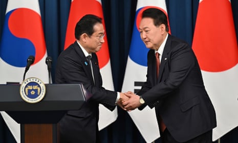 The South Korean president, Yoon Suk Yeol (right), shakes hands with the Japanese PM, Fumio Kishida,  at a press conference in Seoul
