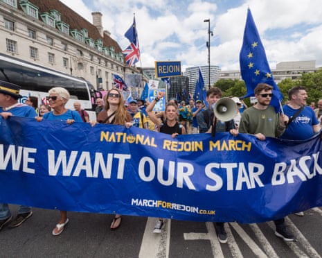 Protesters march holding a large blue banner reading "We want our star back" and EU flags
