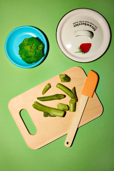 Chopping board with green veg on it and a spatula, with two plates behind