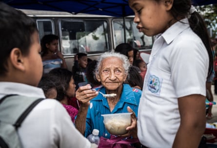 A grandmother feeds her grandchild at a charity kitchen run by volunteers and an NGO. Often, one person in the family ends up sacrificing their meal so that other family members can eat a bit more