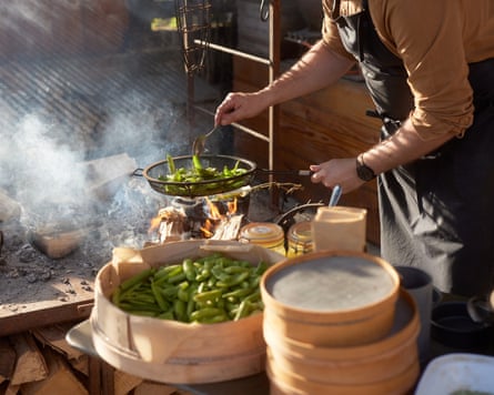 A chef cooks a pan of mangetout over an open flame at Pythouse Kitchen Garden in Wiltshire