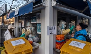 Medical workers reach through protective gloves as they administer Covid-19 nucleic acid tests in Beijing, China.