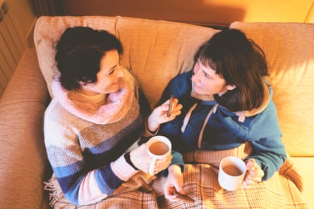 Two women on the sofa, drinking tea and eating biscuits