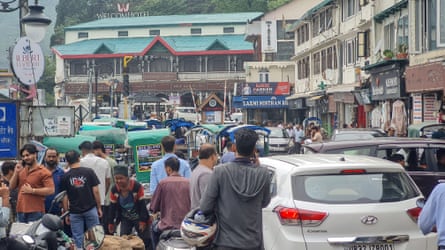 Vehicle and pedestrian traffic moving along a busy road in a small Indian town.