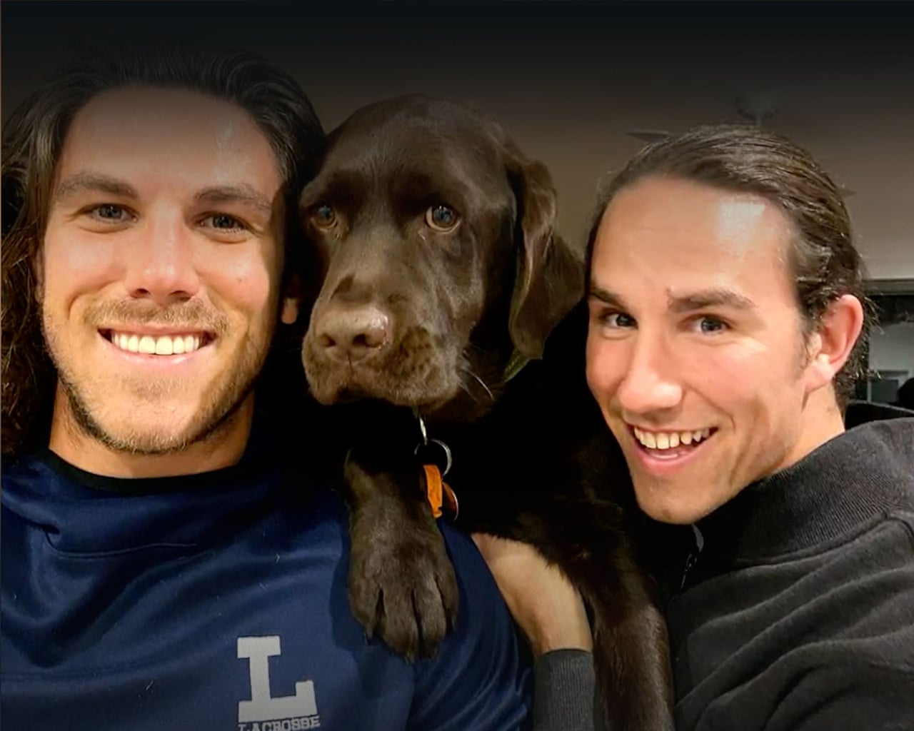 Australian brothers Jake and Callum Robinson, aged 30 and 33, holding a brown dog