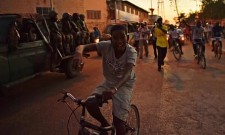 A boy rides a bike near a Senegalese Ecowas vehicle as they arrive at State House in Banjul.