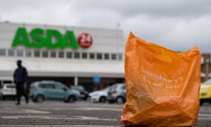A Sainsbury’s shopping bag in front of an Asda supermarket in London, England.