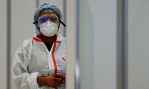 A health worker wearing protective gear waits for passengers to be tested for Covid-19 on arrival at Charles de Gaulle airport near Paris, France.