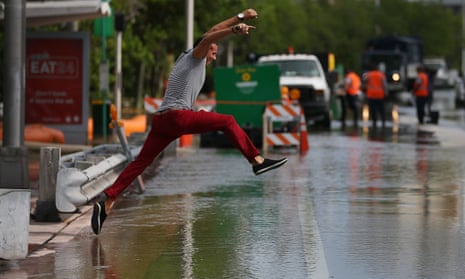 A man tries to jump to a shallow spot as he crosses a flooded street in Miami Beach, Florida, in September.