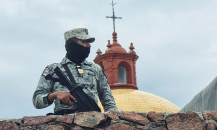 A member of the Mexican army stands guard outside the church where the Jesuit priests were killed.