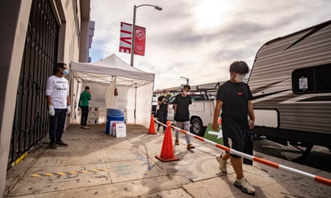 A woman self-tests for coronavirus as people wait their turn at a Covid-19 mobile testing site in Los Angeles, California, at the weekend as the US set a record for new daily cases.