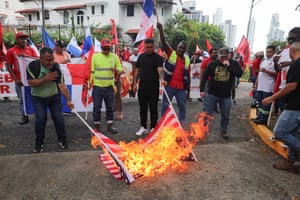 people stand around as an American flag burns on the ground outside