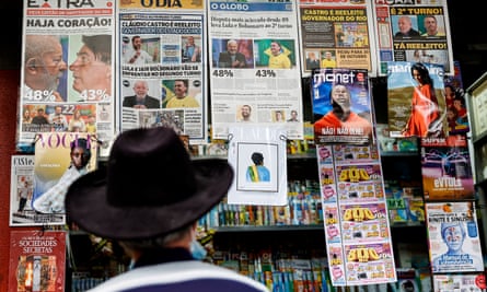 A man looks at Brazilian newspapers at a newsstand showing headlines a day after the general elections in Rio de Janeiro.