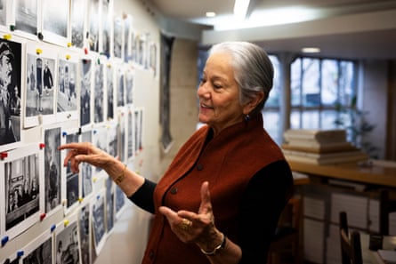 A woman stands facing a board on which photographs have been pinned