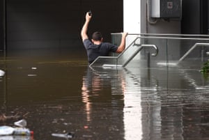 A man wades through flood waters in the Brisbane suburb of Milton