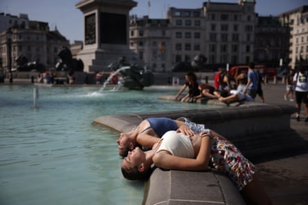 Two women dip their heads into the fountain to cool off in Trafalgar Square on 19 July in London. The Met Office issued its first red extreme heat warning in England, from London and the south-east up to York and Manchester