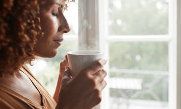 A woman smelling a cup of coffee