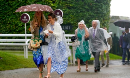 Racegoers shelter from the rain during the Goodwood Festival at Goodwood Racecourse.