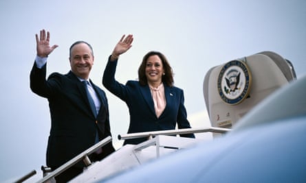 A man and a woman smile and wave before boarding a plane.