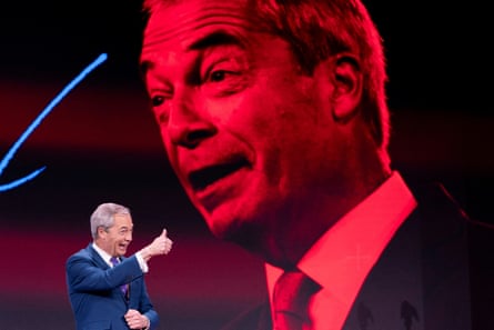 Nigel Farage bën shenjën e gishtit të madh lart në skenë me një portret të madh të kuq të fytyrës së tij nga pas.
