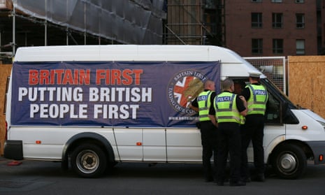 A van with a large Britain First banner saying 'Putting British people First' with a group of police officers apparently speaking to the driver
