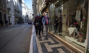People in blue masks walk the cobbled streets of Lisbon, Portugal on 26 November.
