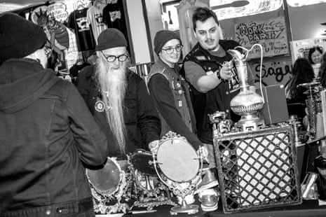 A black-and-white image of people handling and viewing silver and mirrored items on a table.