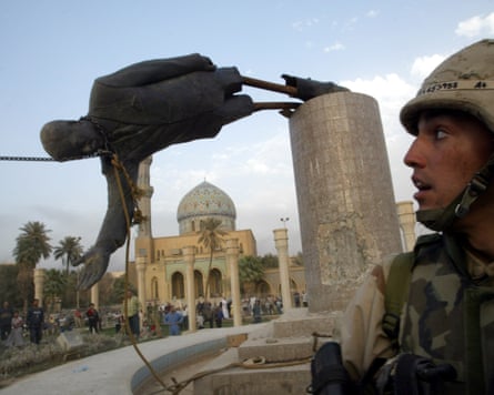 An American soldier watches as a statue of Saddam Hussein falls in central Baghdad, April 2003.