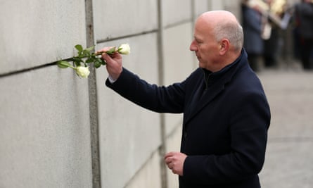 Berlin’s mayor, Kai Wegner, places a rose in between sections of a portion of the former Berlin Wall.