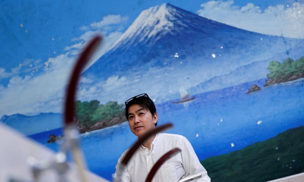 Man stands in front of a painting of Mount Fuji