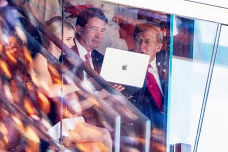 US president Donald Trump looks at a laptop held by his executive assistant Natalie Harp alongside Tennessee senator Bill Hagerty during the Tennessee-Texas game at Neyland Stadium.