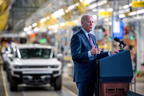 a man in a blue suit speaks in a car factory